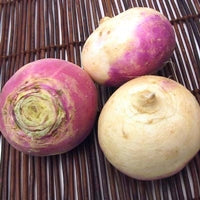 A 2 part image showing peeled turnips being sliced on a mandoline